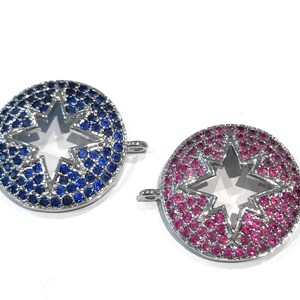 Pu&ograve; includere: Due ciondoli rotondi argentati con un ritaglio a forma di stella al centro. Un ciondolo &egrave; decorato con cristalli blu e l'altro con cristalli rosa.