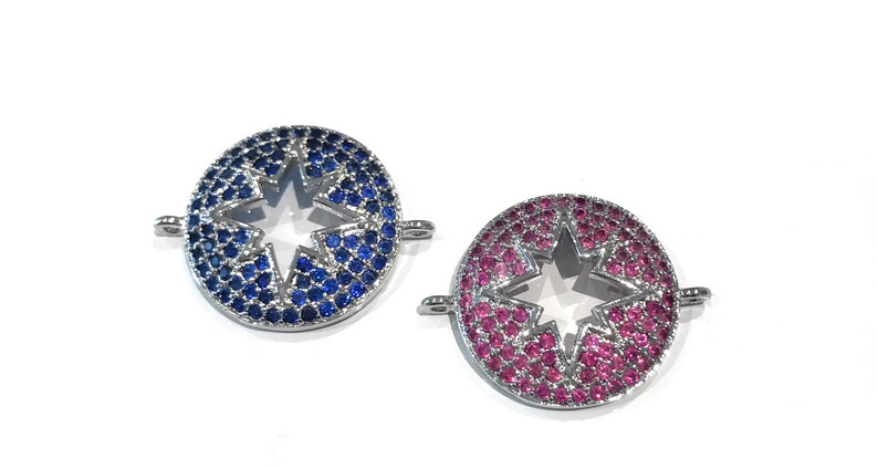 Pu&ograve; includere: Due ciondoli rotondi argentati con un ritaglio a forma di stella al centro. Un ciondolo &egrave; decorato con cristalli blu e l'altro con cristalli rosa.