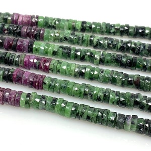 May include: A strand of green and pink gemstone beads. The beads are faceted and have a slightly irregular shape. The beads are strung on a clear thread.