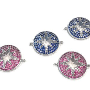Pu&ograve; includere: Tre ciondoli a forma di stella argentati con centri in cristallo trasparente. I ciondoli sono circondati da strass blu e rosa.