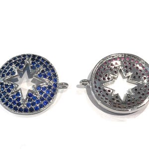 Pu&ograve; includere: Due ciondoli in metallo color argento con un ritaglio a forma di stella al centro. Un ciondolo &egrave; decorato con strass blu e l'altro con strass rosa.