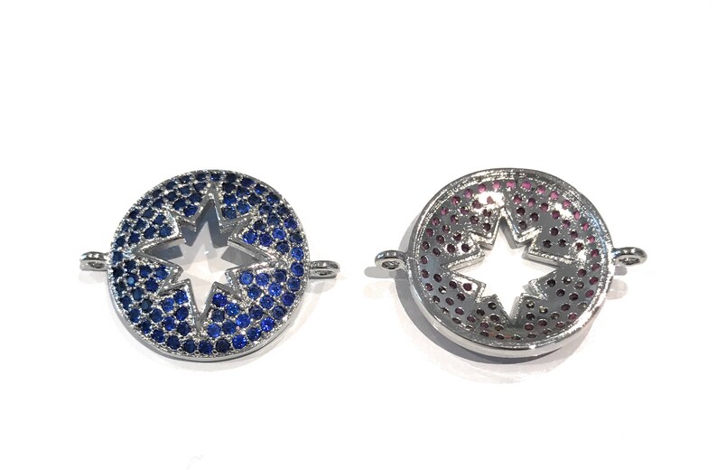 Pu&ograve; includere: Due ciondoli in metallo color argento con un ritaglio a forma di stella al centro. Un ciondolo &egrave; decorato con strass blu e l'altro con strass rosa.