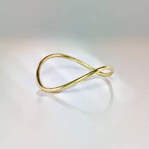 May include: A simple gold ring with a unique infinity symbol design.