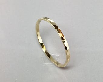 May include: A thin gold band ring with a hammered texture.