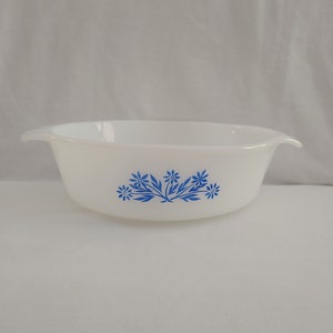 May include: White ceramic baking dish with a blue floral design. The dish has two handles on the sides.
