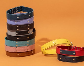 Puede incluir: Una pila de collares personalizados para perros en varios colores, incluyendo turquesa, rosa y marrón, con nombres como "Sparki" y "Daniel" grabados en el cuero. Se muestran collares adicionales en amarillo, rojo y azul marino.