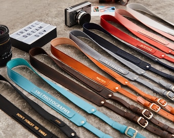 May include: A selection of leather camera straps with personalised text, including "Travelgang", "Justice", "SWJ Photography", and "Don't Forget to Smile".