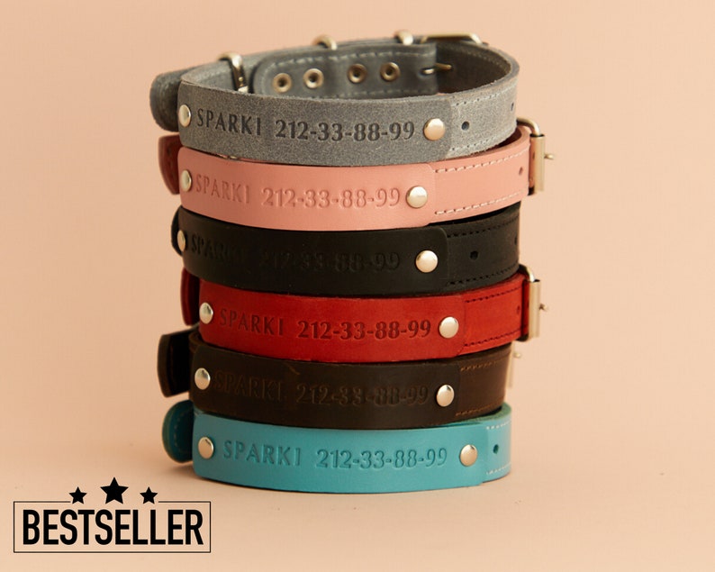 Puede incluir: Una pila de collares de cuero para perros en varios colores, incluyendo gris, rosa, negro, rojo, marr&oacute;n y turquesa. Cada collar est&aacute; grabado con el nombre "SPARKI" y un n&uacute;mero de tel&eacute;fono. Los collares tienen herrajes met&aacute;licos plateados.