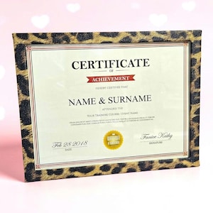 May include: A rectangular certificate of achievement displayed in a frame with a black and gold leopard print pattern. The document features the text Certificate of Achievement, Name & Surname, and a gold seal, dated Feb 28 2018 with a signature.