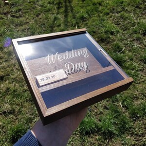 Peut inclure: Une boîte en bois avec un couvercle en verre, gravée des mots "Wedding Day" et de la date "29.02.20".