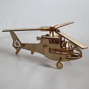May include: A wooden model helicopter with a natural wood finish. The helicopter features a detailed design, including a main rotor, tail rotor, and windows. The model is constructed from interlocking wooden pieces and is suitable for display or as a craft project.