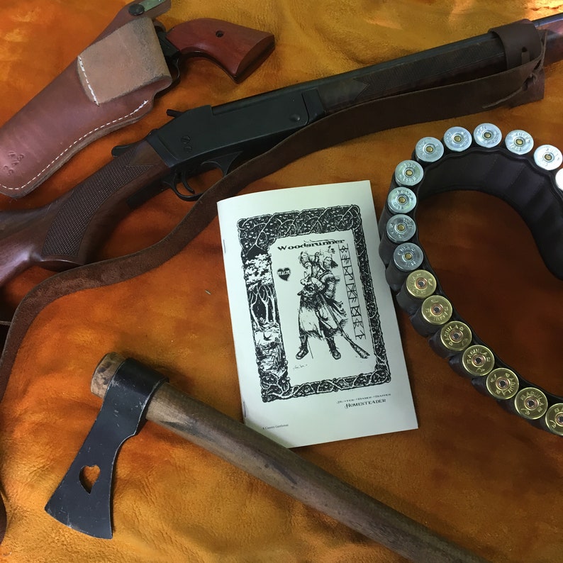 May include: A black shotgun with a brown leather strap, a brown leather holster with a black and brown pistol, a black tomahawk with a brown wooden handle, and a booklet with the title "Woodcarver" and the text "Homesteader" on a brown fabric background. The booklet has a black and white illustration of a person holding a weapon.