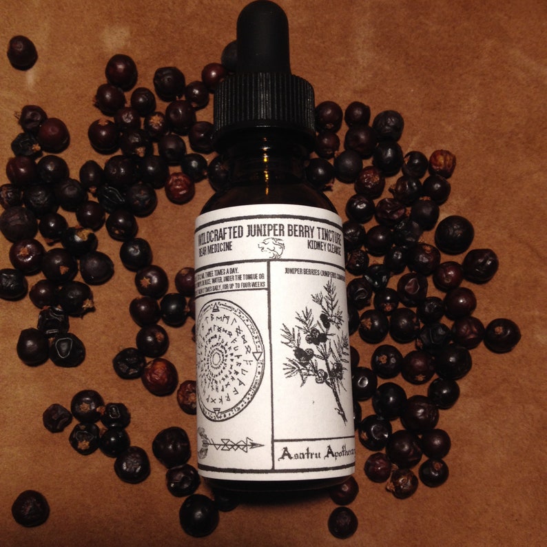 May include: A glass bottle with a black dropper top and a white label. The label reads "Wildcrafted Juniper Berry Tincture Herbal Medicine Kidney Cleanse". The bottle is surrounded by dark blue berries.