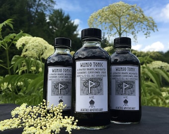 May include: Three dark glass bottles of "Wunjo Tonk" with black caps and white labels, each containing a dark liquid. The labels include text and a symbol. The bottles are 4 oz. each. The background features greenery and a blue sky.