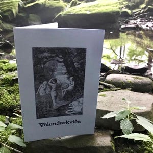 May include: A white booklet with the title "Völundarkvíða" printed in black. The cover features a black and white illustration of three women in a forest setting.