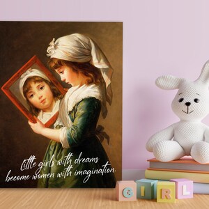 May include: A framed print of a classical painting shows a young girl in a white bonnet and green dress, holding a mirror. The mirror reflects her face. The text reads: "Little girls with dreams become women with imagination."