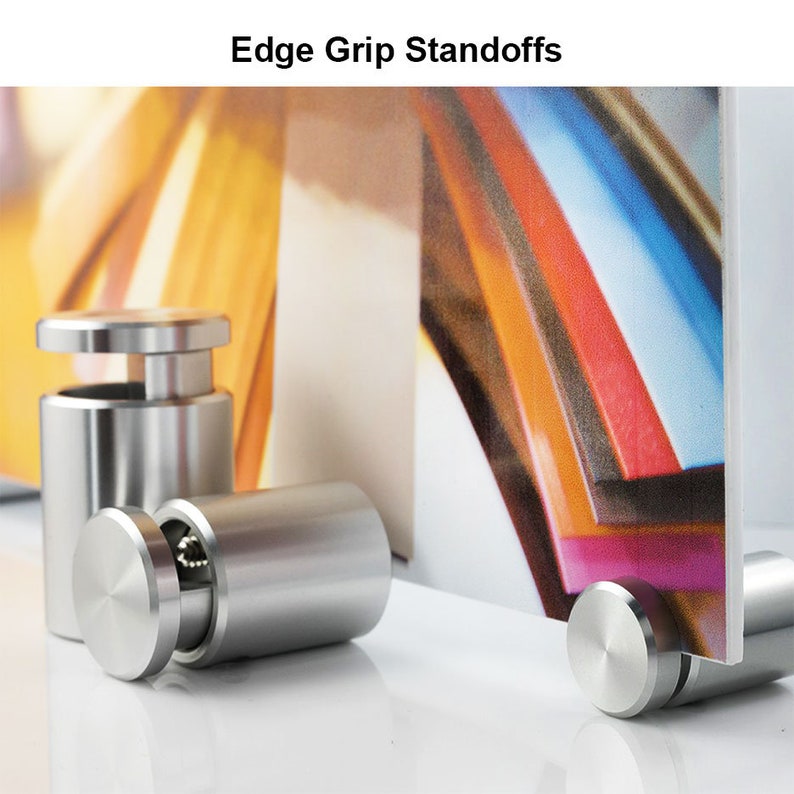 Puede incluir: Se muestran varios separadores cil&iacute;ndricos de metal cepillado. Los separadores tienen una parte superior e inferior planas y circulares, con un centro roscado. El texto "Edge Grip Standoffs" est&aacute; en la parte superior de la imagen. Soportan un panel.