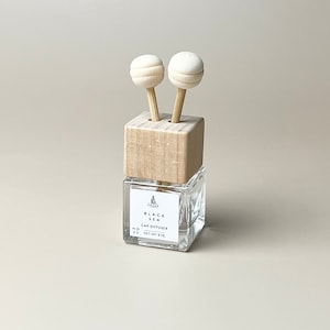 以下が含まれることがあります： 木製の蓋と2本の木製のスティックが付いたガラス製の車のディフューザーボトル。ボトルには「Black Sea Car Diffuser」と「No. 23 Net Wt 8 ml」のラベルが貼られています。