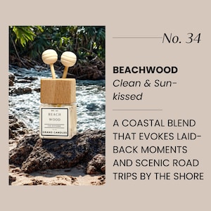 May include: A car air freshener with a wooden top and two wooden sticks. The label reads "Beach Wood" and "Grand Candles." The background shows a natural coastal scene with water and rocks. The text on the right says "Clean & Sun-kissed."