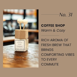 May include: A square glass car diffuser with a wooden top and two white wooden sticks. The label reads "COFFEE SHOP" and "GRAND CANDLES". The text on the image says "Warm & Cozy" and describes the aroma of fresh brew.