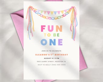 May include: A white invitation card with the text "FUN TO BE ONE" in colourful letters, decorated with a garland of colourful flags and ribbons. The invitation is for Eleanor's 1st birthday, with date, time, and location details.
