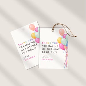 Può includere: Due etichette regalo bianche con la scritta "THANK YOU FOR MAKING MY BIRTHDAY SO BRIGHT! LOVE, ELEANOR" in colori pastello. Ogni etichetta presenta un'illustrazione ad acquerello di palloncini colorati. Un'etichetta ha uno spago marrone.