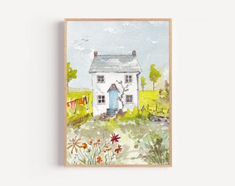 May include: Watercolor painting of a white two-story house with a blue door and gray roof, set in a green field with flowers. The artwork is framed in a light brown wooden frame. Clothes hang on a clothesline.