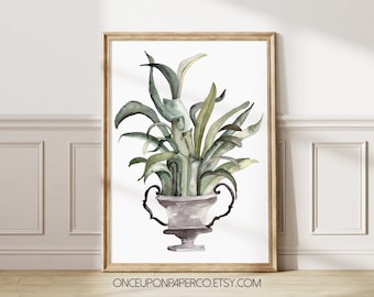 May include: Watercolor print of a plant in a gray urn with handles, set against a white background. The plant features green and gray leaves. The artwork is framed in a light brown wooden frame. The Etsy shop name is visible at the bottom.