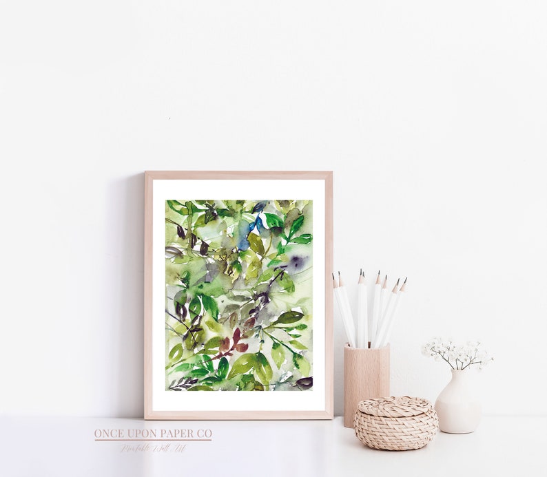 May include: A framed watercolor painting of green leaves and branches in shades of green, blue, and brown. The painting is set against a white background.