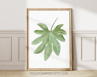 May include: A watercolor painting of a single green leaf in a light wood frame. The leaf is a light green color and has a unique shape with many points. The background is white.