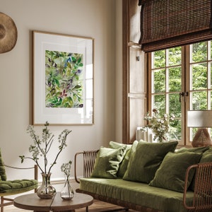 May include: A living room with a green velvet sofa, a wooden coffee table, and a framed watercolor painting of green leaves. The room has a large window with a wooden blind and a view of trees outside.