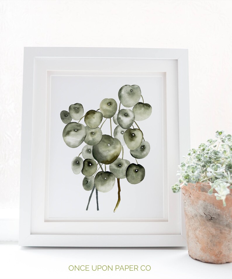 May include: A watercolor painting of a string of green and brown round leaves, framed in a white frame. The painting is titled "Once Upon Paper Co."