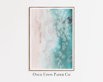 May include: Abstract watercolor art print in a wooden frame. The artwork features a blend of teal, light blue, and beige hues, creating a serene, ocean-inspired aesthetic. The text "Once Upon Paper Co" is printed at the bottom.