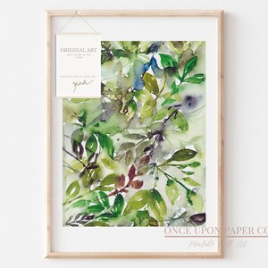 May include: Framed watercolor painting of green leaves in various shades of green, brown, and blue. The painting is titled "Once Upon Paper Co.  Prints" and is signed "Gina".