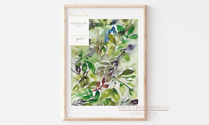 May include: Framed watercolor painting of green leaves in various shades of green, brown, and blue. The painting is titled "Once Upon Paper Co.  Prints" and is signed "Gina".