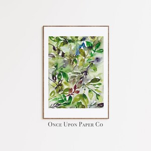 May include: A watercolor painting of green leaves in various shades of green, blue, and brown. The painting is framed in a wooden frame and has the text "Once Upon Paper Co" at the bottom.