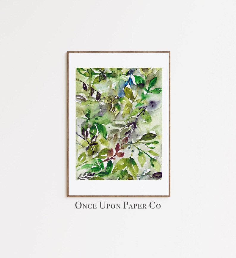 May include: A watercolor painting of green leaves in various shades of green, blue, and brown. The painting is framed in a wooden frame and has the text "Once Upon Paper Co" at the bottom.