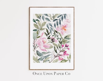 May include: Watercolor painting of pink flowers and green leaves on a white background. The painting is framed in a light brown frame. The text "Once Upon Paper Co" is printed below the frame.