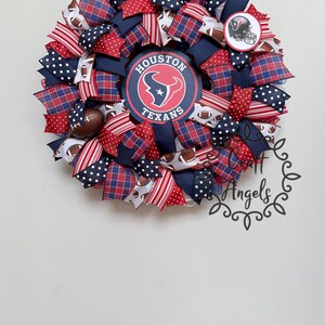 May include: A decorative wreath featuring the Houston Texans logo in the centre, surrounded by red, white, and navy blue mesh ribbons. The design includes patterns of polka dots, plaid, and footballs, with a small Texans helmet emblem.