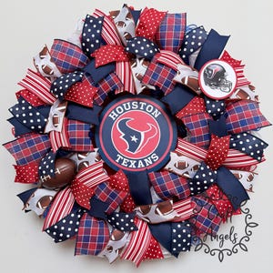 May include: A decorative wreath featuring the Houston Texans logo in the centre and a smaller team helmet emblem. The design incorporates ribbons in navy blue, red, and white, with patterns including polka dots, plaid, stripes, and football graphics.