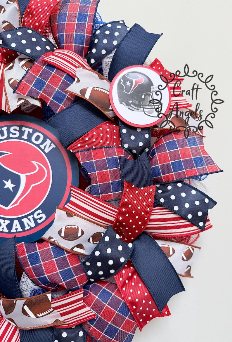 May include: A decorative wreath featuring Houston Texans branding with a large circular logo and a smaller football helmet emblem. The design incorporates ribbons in red, white, and navy blue with patterns including polka dots, plaid, stripes, and footballs.