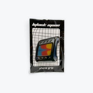 May include: Black phone grip with a colorful retro TV screen design. The grip is packaged in a black plastic bag with the text "black moon" and "phone grip".