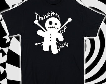 May include: Black t-shirt with a white graphic of a voodoo doll with needles and the text "Thinking of you".