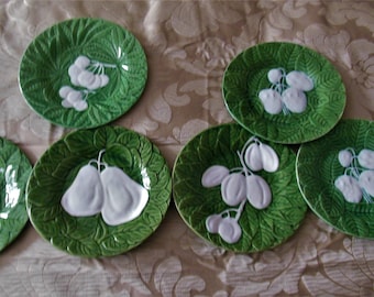 Puede incluir: Juego de seis platos de cerámica verde y blanca con un diseño en relieve de frutas y hojas. Los platos son todos del mismo tamaño y forma, y están dispuestos en círculo.