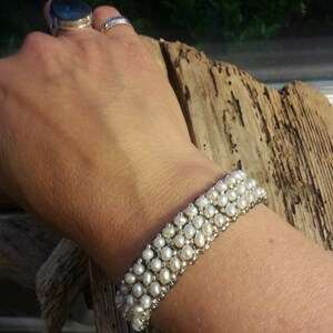 May include: A white pearl bracelet with multiple rows of pearls. The bracelet is made with small, round pearls and silver beads.