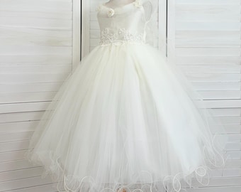 May include: A white tulle dress with a lace bodice and a satin sash. The dress has a scalloped hem and is perfect for a special occasion.