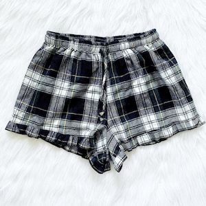 Puede incluir: Pantalones cortos de pijama de cuadros negros y blancos con un dobladillo con volantes.