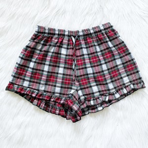 Puede incluir: Pantalones cortos de pijama de cuadros rojos, verdes y blancos con un dobladillo con volantes.
