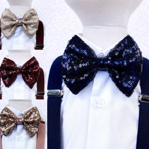 May include: Three different bow ties with sequin embellishments. The bow ties are in navy blue, burgundy, and gold. Each bow tie is attached to a pair of suspenders.