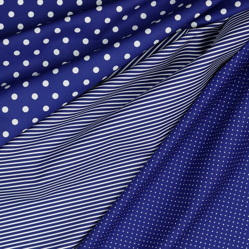 May include: Three different blue fabrics with white patterns. The top fabric has large white polka dots, the middle fabric has thin white stripes, and the bottom fabric has small white polka dots.